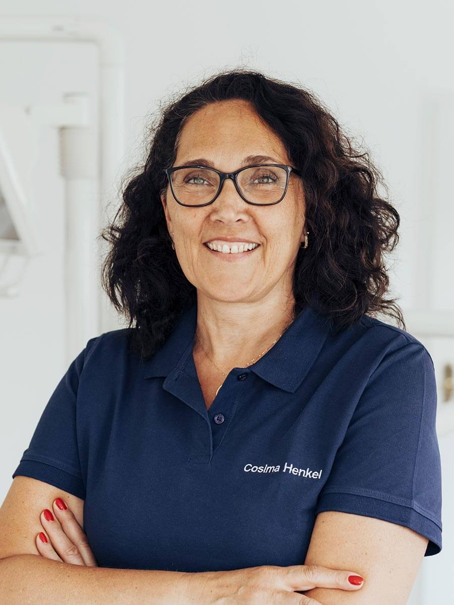 Empfangsdame Cosima lächelt mit verschränkten Armen in die Kamera.
