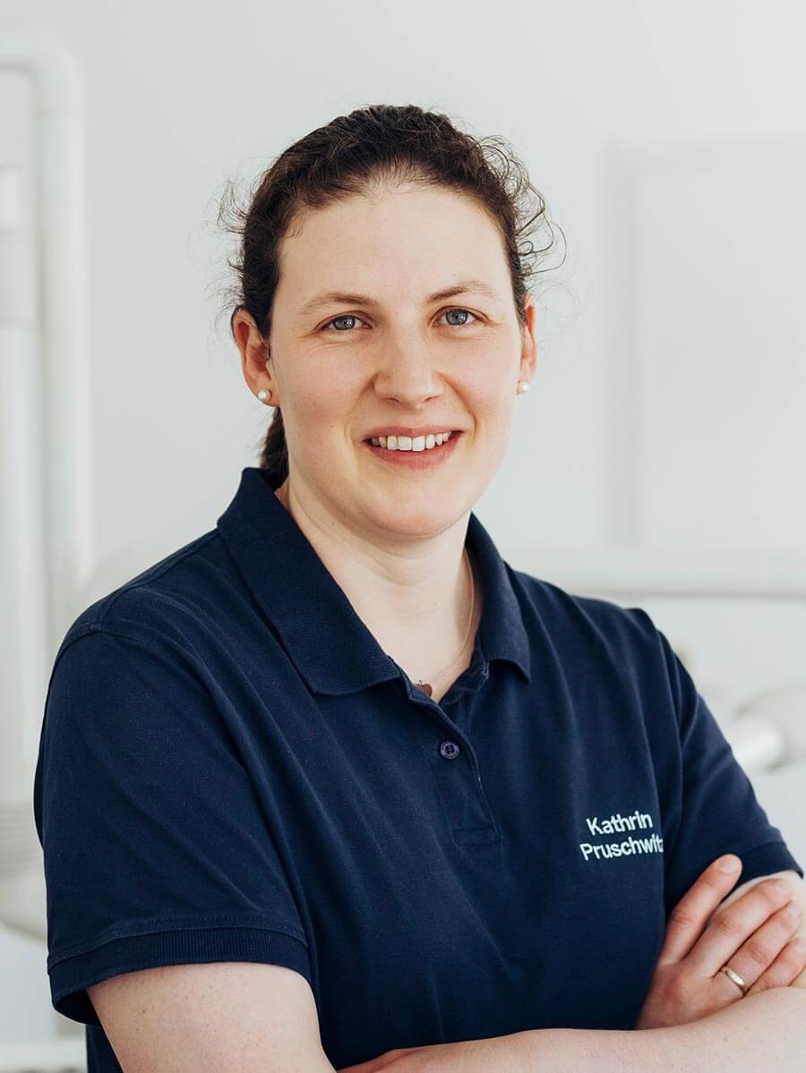 Assistenz Kathrin lächelt mit verschränkten Armen in die Kamera.
